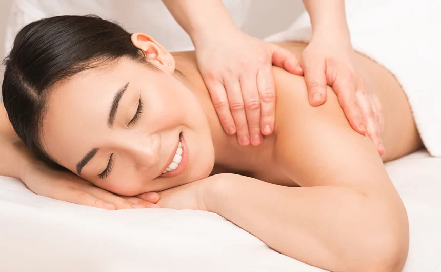 Smiling woman enjoying a relaxing back massage on white spa bed during wellness treatment session