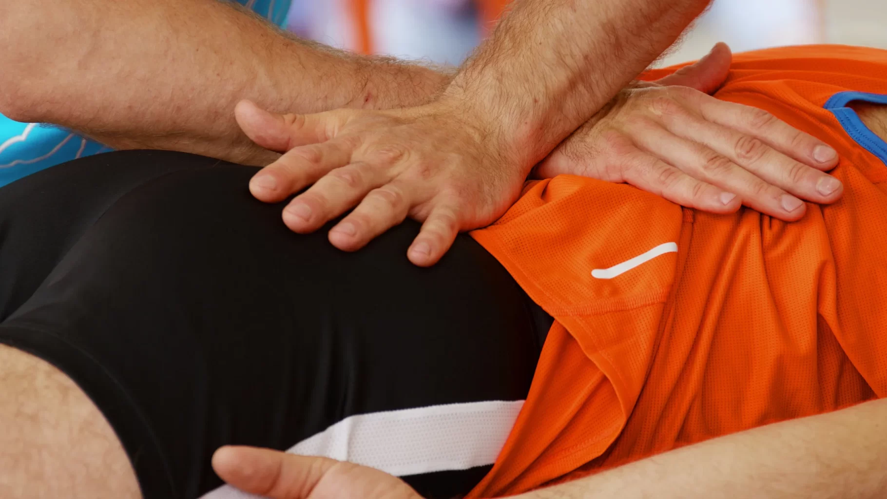 Physical therapist applying manual pressure to athlete’s hip and lower back during recovery