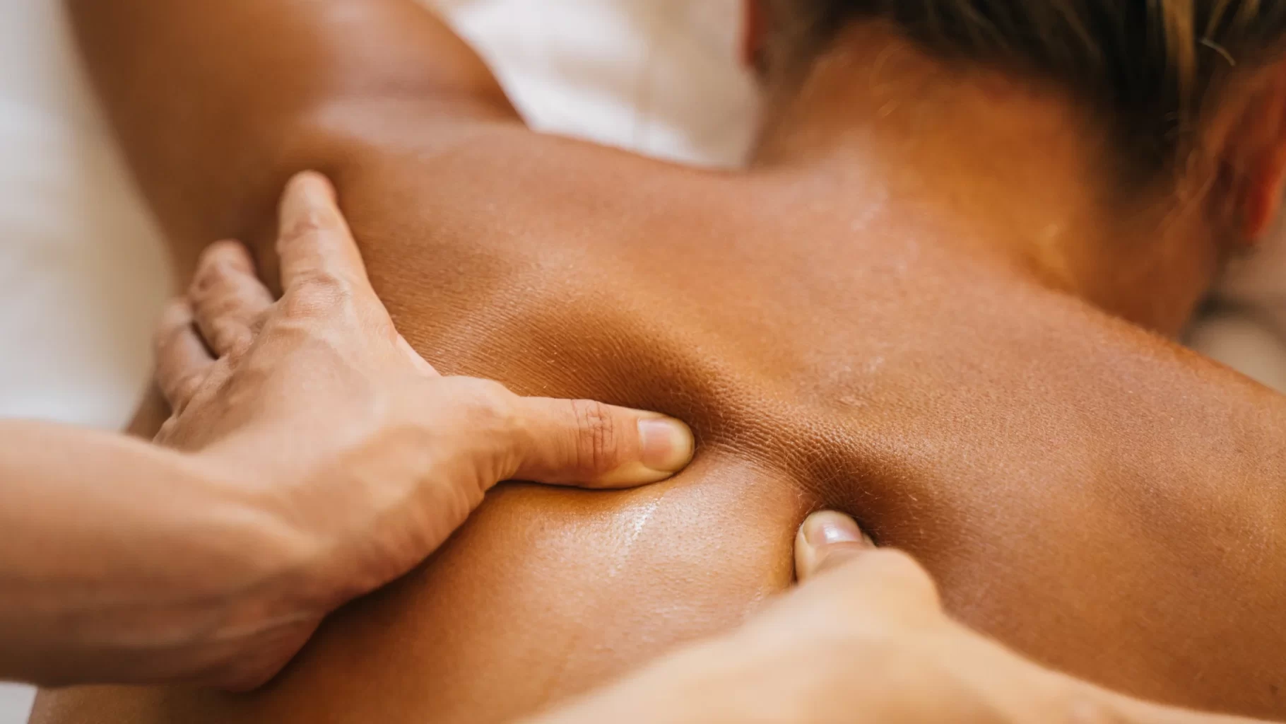 Massage therapist applying deep pressure to upper back during relaxing wellness treatment care