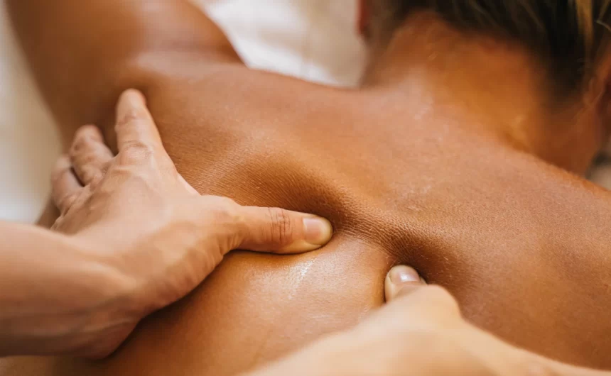 Massage therapist applying deep pressure to upper back during relaxing wellness treatment care
