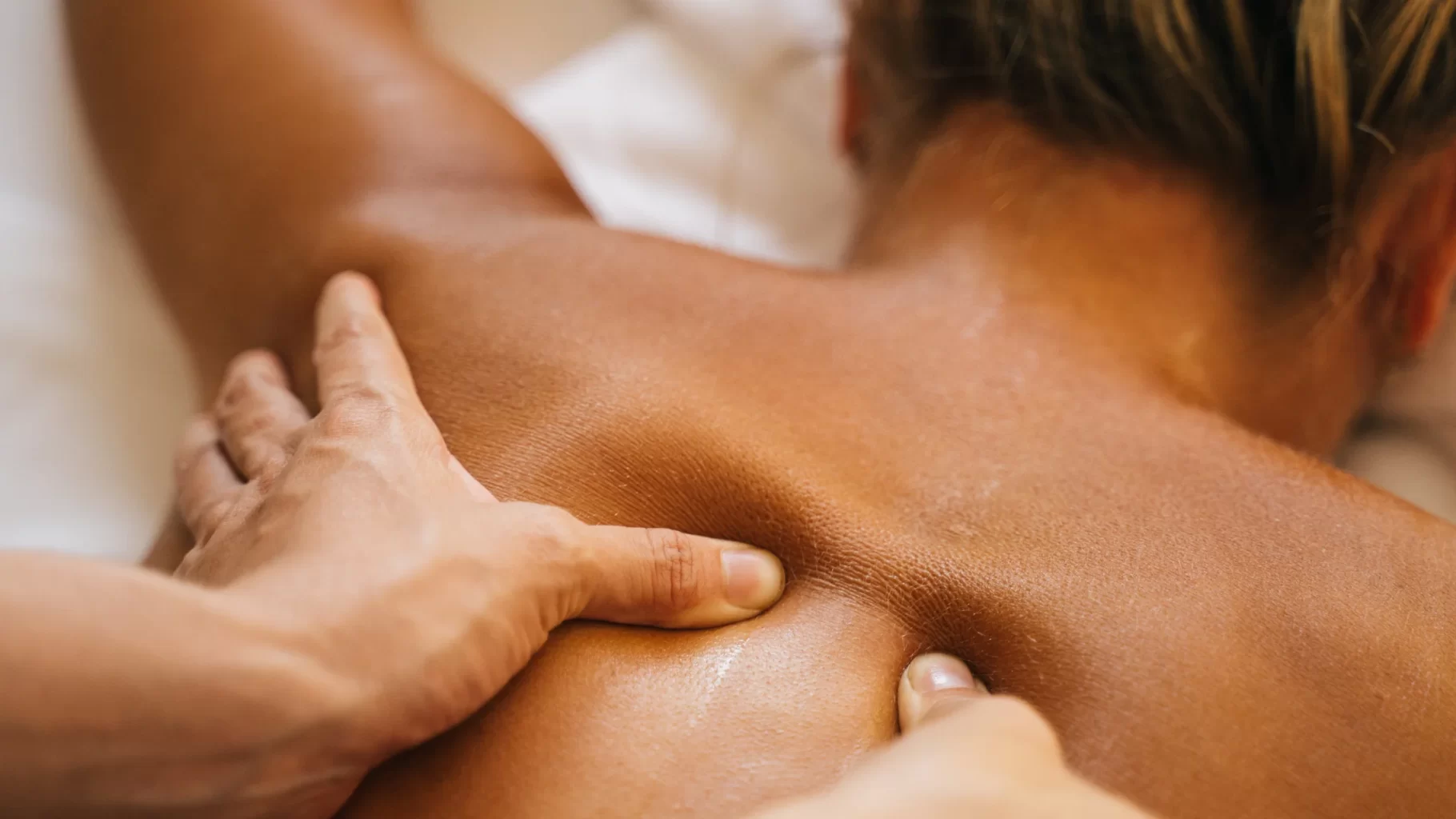 Massage therapist applying deep pressure to upper back during relaxing wellness treatment care