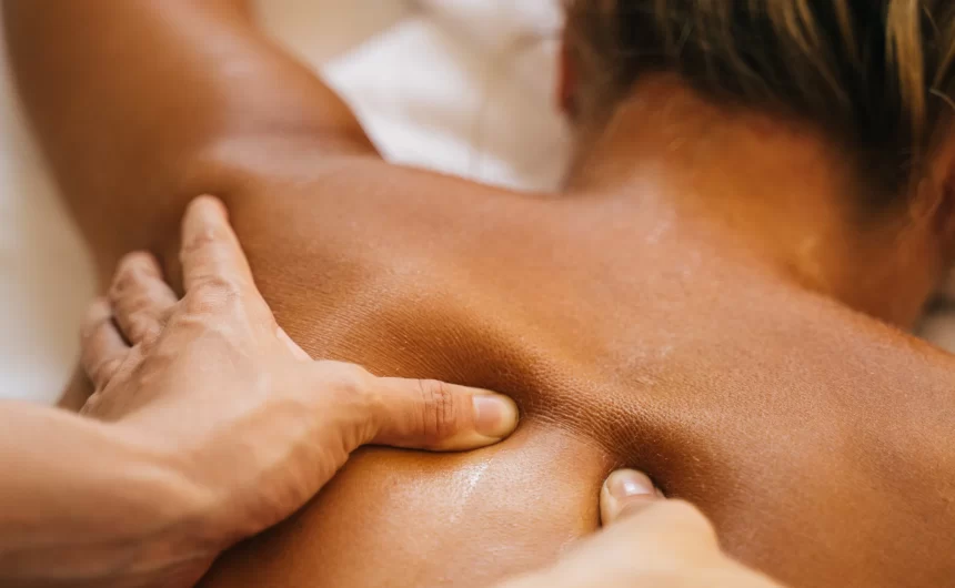Massage therapist applying deep pressure to upper back during relaxing wellness treatment care