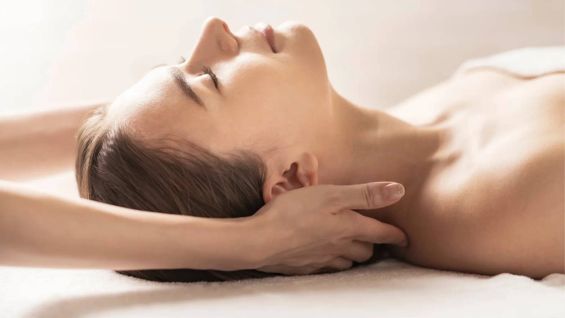 Woman receiving gentle neck massage while resting peacefully during a spa wellness session