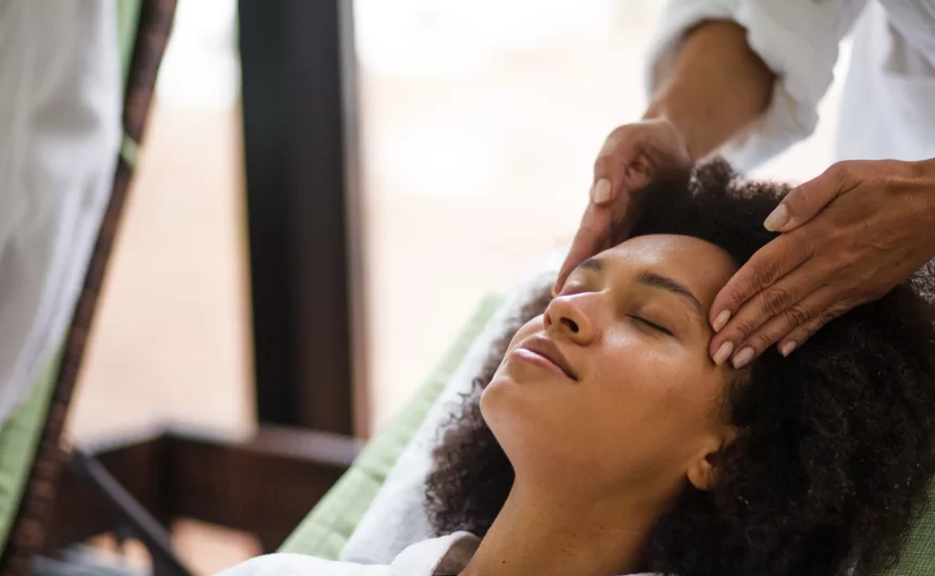 Woman relaxing with eyes closed during calming scalp and facial massage at a wellness spa visit