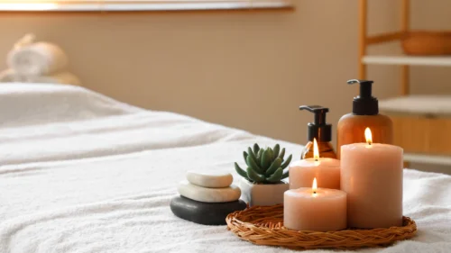 Calming spa treatment room with massage table, candles, stacked stones, succulent, and amber lotion bottles.