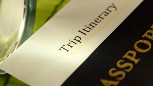 Close-up of a trip itinerary beside a passport, suggesting a relaxing wellness spa getaway or travel retreat.